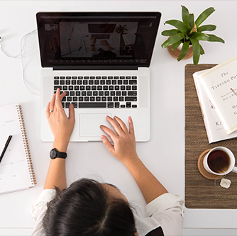 Mesa de escritório com notebook e mulher digitando